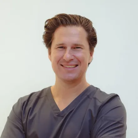 Dr. Christian Wolf in grey scrubs, arms folded