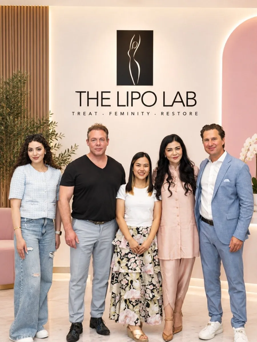 فريق The Lipo Lab المكوّن من خمسة أشخاص واقفاً معاً في استقبال العيادة أسفل لافتة العيادة