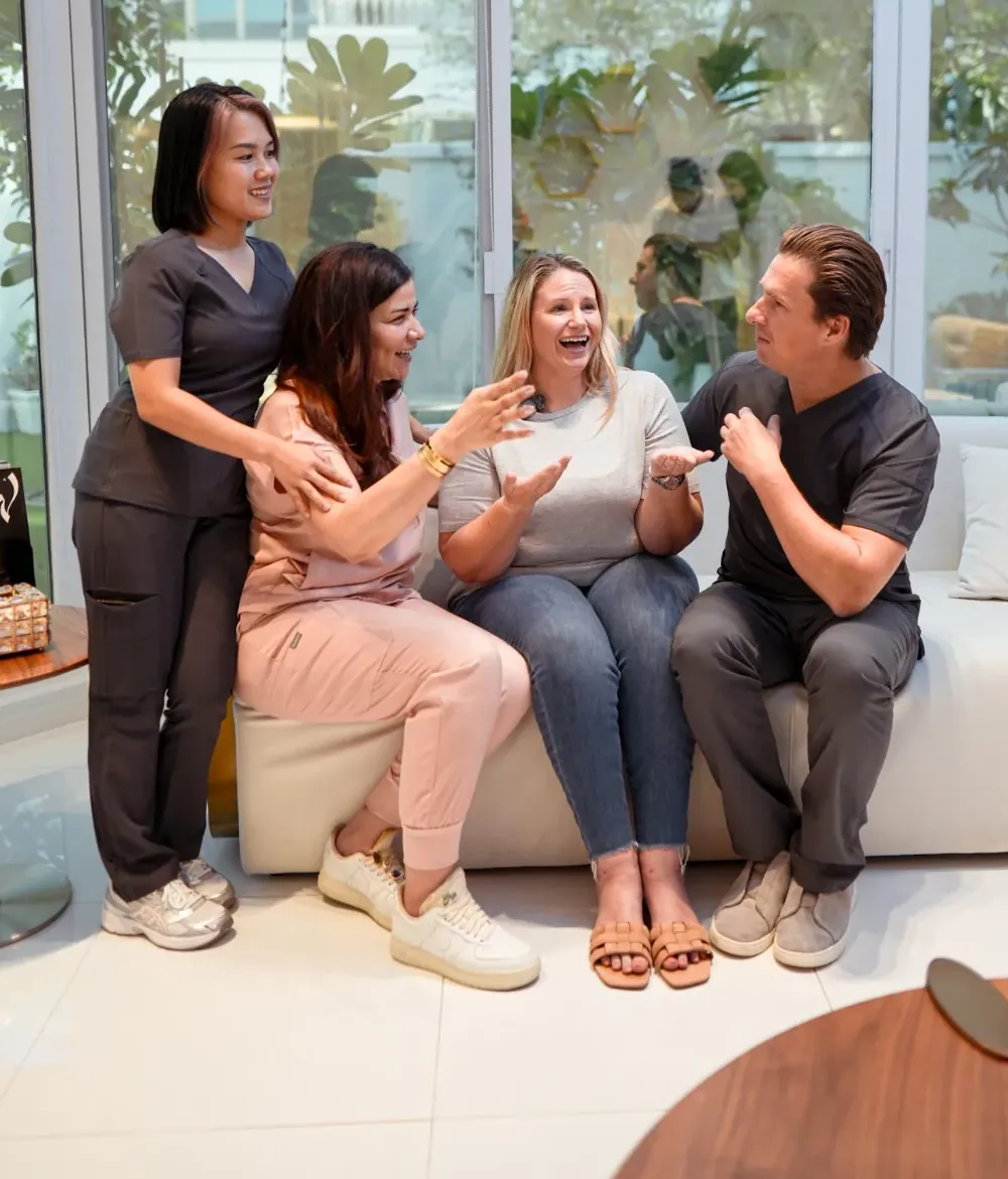 The Lipo Lab team and a patient laughing together on a clinic sofa